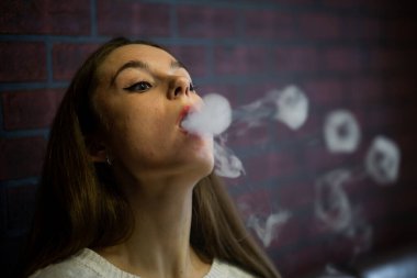 Buharlı genç. İçeride elektronik sigara içen, beyaz tenli, beyaz, genç bir kız. Hayati tehlikesi olan kötü alışkanlık. Vestiyer etkinliği.