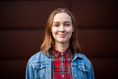 Duygular. Gülümse. Ergen. Gündelik kot ceketli, beyaz, genç, güzel bir kız sonbaharda karanlık, modern bir grupla caddenin ortasında..