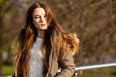 Sonbahar trendi yeşil kıyafet modeli. Genç, beyaz, beyaz, yeşil ceketli, güneşli bir sonbaharda sokakta dolaşan genç bir kız..