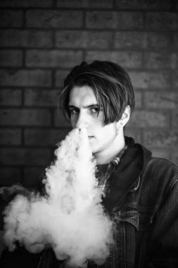 Buharlı genç. Barda sigara içen yakışıklı bir gencin portresi. Sağlığa zararlı olan tehlikeli bir alışkanlık. Vestiyer aktivitesi. Siyah taşak beyazı.