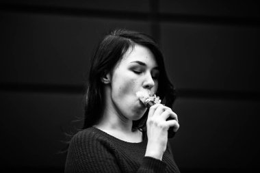 Derisi sorunlu bir genci buharlaştırmak. Ceketli, beyaz, genç ve güzel bir kız akşamları sokakta modern kahverengi arka planda elektronik sigara içiyor. Çok kötü bir alışkanlık. Siyah ve beyaz