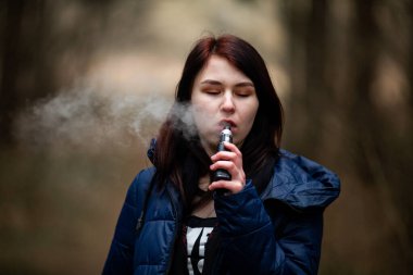 Genç bir erkek. Genç, beyaz, esmer, güzel bir kız baharda sokakta elektronik sigara içiyor. Çok kötü bir alışkanlık..