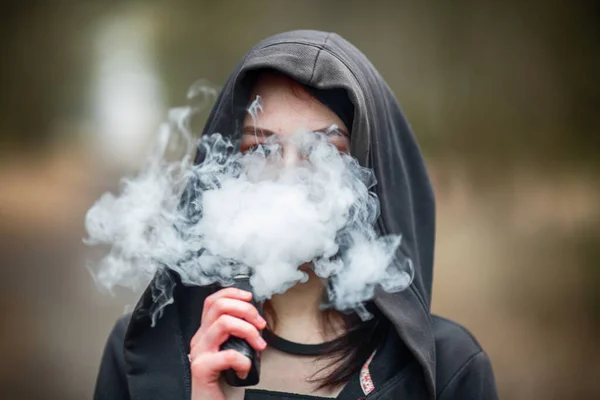 10代になると 若いかなり白人のブルネットの女の子は春に路上で電子タバコを吸う 致命的な悪い習慣 ストック画像