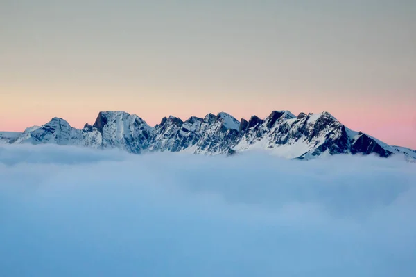 冬のスイス アルプスの雲銀行の厚いカバーの上ソフト夜の光の山の風景 — ストック写真