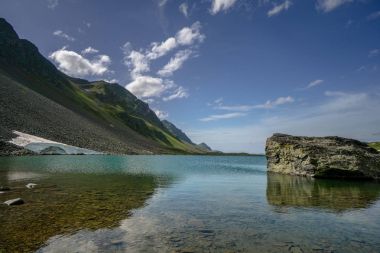 büyük bir kaya ve yansımaları Davos İsviçre Alpleri'nde yakınındaki güzel dağ gölü