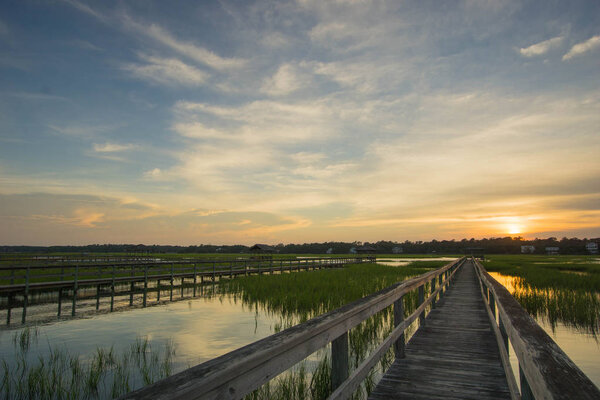 boardwalk over creek and barrier island at high tide at sunset under a beautiful evening sky