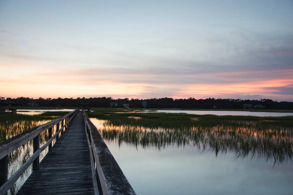 boardwalk over creek and barrier island at high tide at sunset under a beautiful evening sky