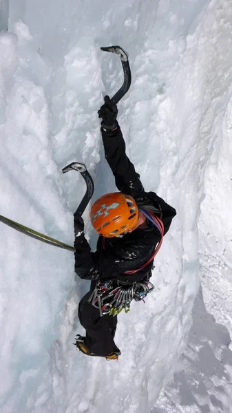 male mountain climber ice climbing on a frozen waterfall in winter in the mountains of Switzerland