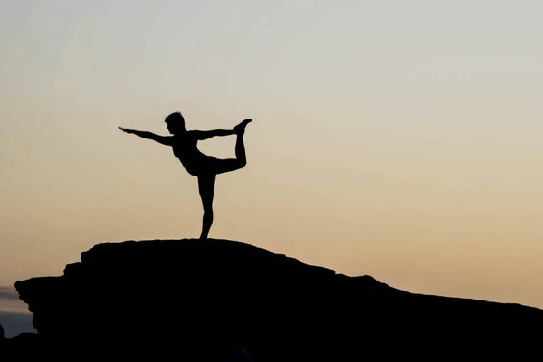 young woman striking a yoga pose on a rock near Horseshoe Bend during a morning yoga session