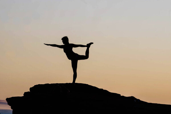 young woman striking a yoga pose on a rock near Horseshoe Bend during a morning yoga session