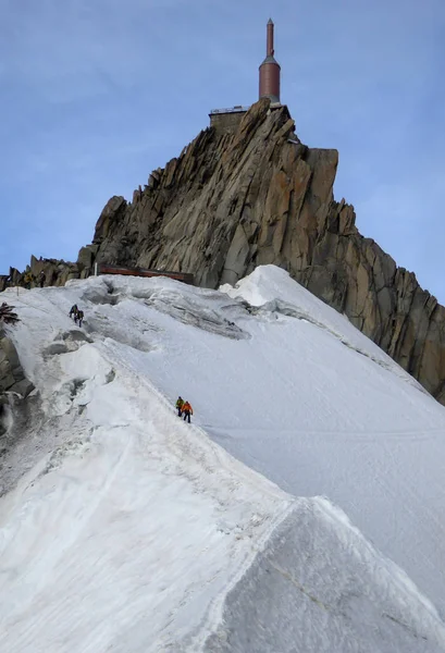 mountain guide and client descending a narrow snow ridge from a mountain summit in the French Alps near Chamonix