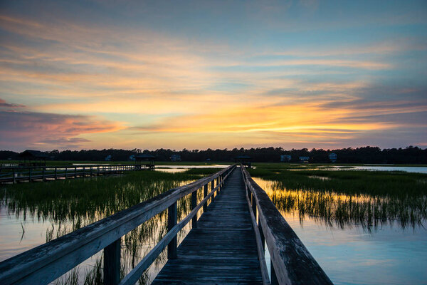 boardwalk over marshlands with a beautiful sunset evening sky