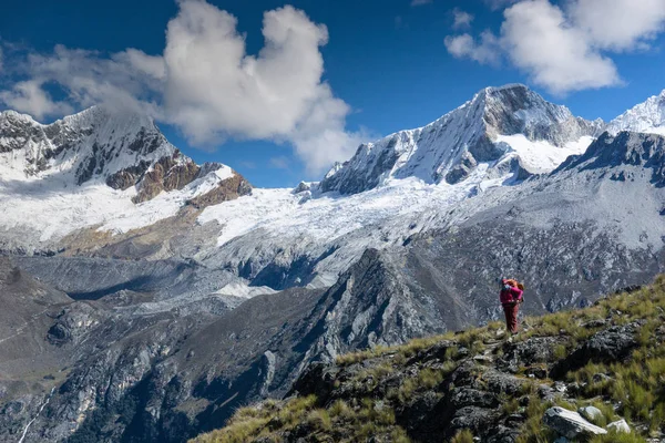 female backpacker standing on a grassy outlook and admiring the fantastic view of the mountain landscape of the Cordillera Blanca in Peru