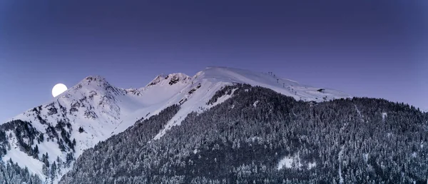 在瑞士阿尔卑斯山 满月落在雪山后面 森林和滑雪升降机在前景 — 图库照片