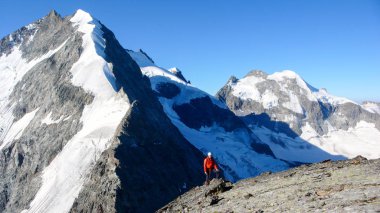 dağcı bir büyük kar ridge ve Peyzaj arkasında yüksek bir dağ tepe üzerinde kırmızı ayakta