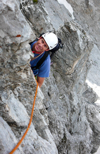 male rock climber on a steep rock climbing route looking up at the next move