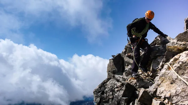 mountain guide on a rocky summit ridge under blue sky