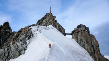 dağ Rehberi ve onların arkasında ünlü Aiguille du Midi yakınındaki Chamonix ile Fransız Alpleri'nde dar ve savunmasız kar sırt üzerinde azalan istemci