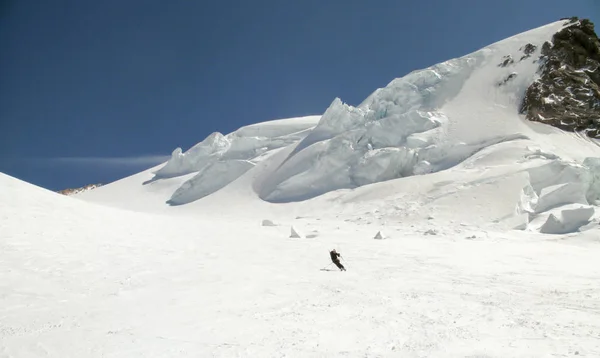 back country skier skiing down a huge alpine glacier on a beautiful winter day with hanging ice seracs behind him