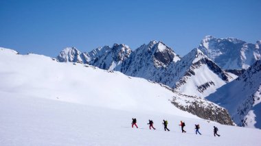 group of backcountry skiers crossing a glacier on their way to a high summit in the Alps clipart