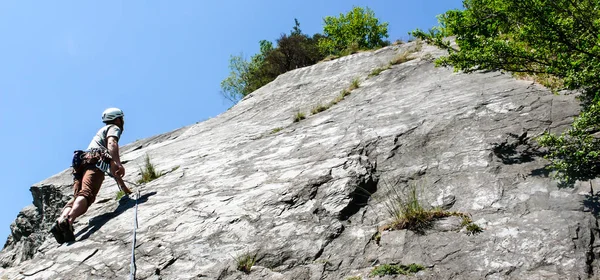 mountain guide rock climber on a slab limestone climbing route in the Alps of Switzerland on a beautiful day