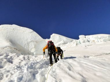 dağ Rehberi ve istemci bir buzulun üzerinde güzel bir yüksek bir dağ Zirvesi doğru yukarı yaz sabahı başlığı