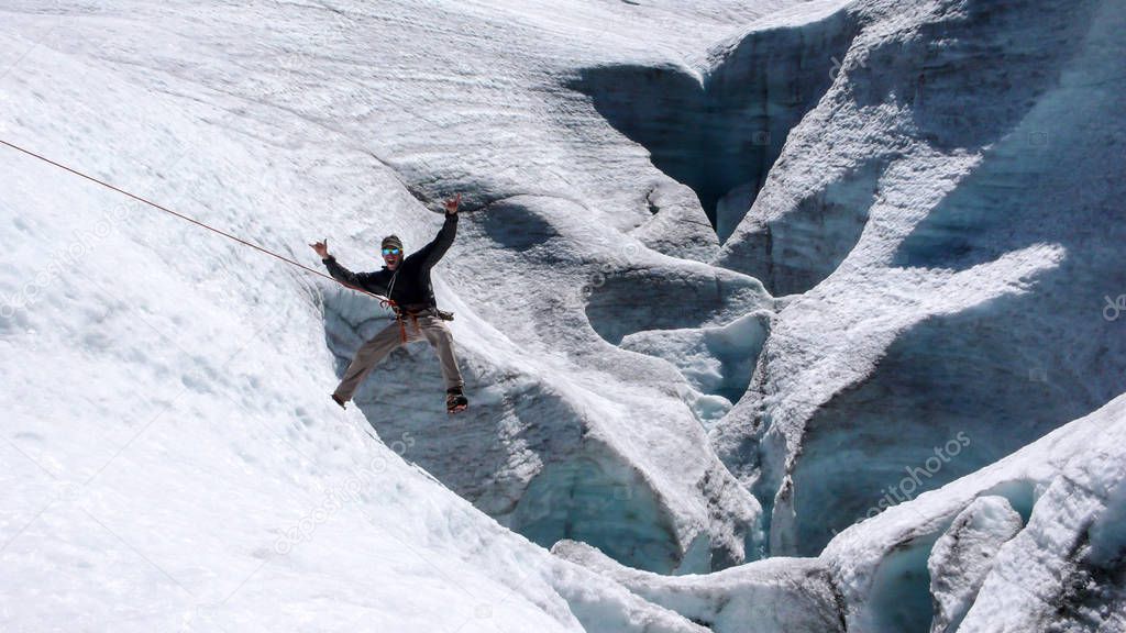 male mountain guide playing around during a crevasse recue exercise on a glacier in the Alps