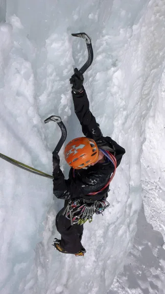 male ice climber on a steep frozen waterfall on a beautiful winter day in the Swiss Alps