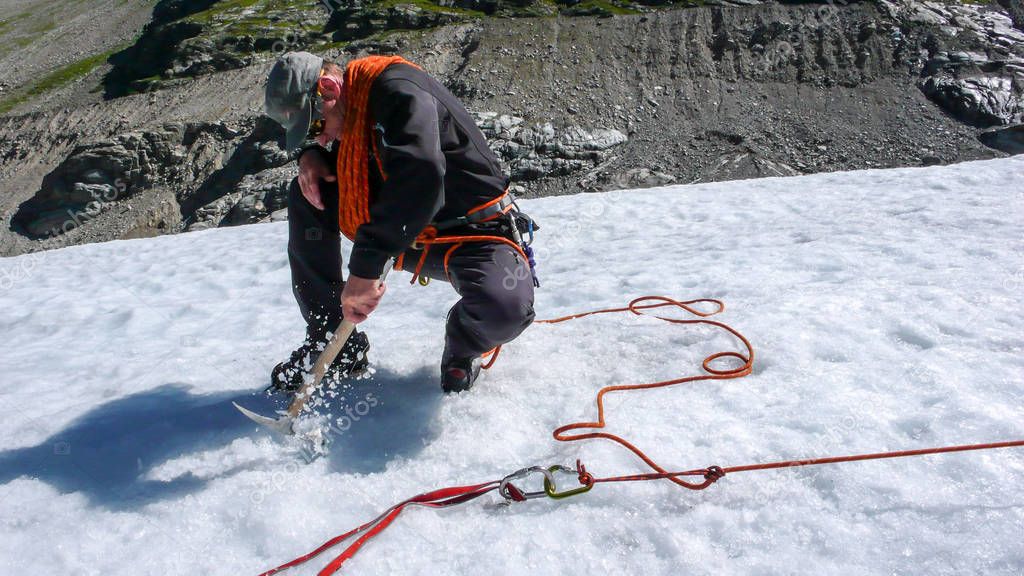 one male mountain guide installing a pulley system for crevasse rescue on a glacier