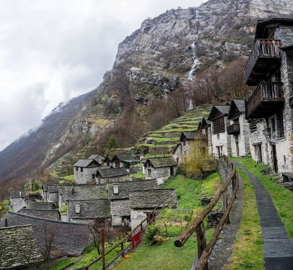 多くの小さな木や石の家と山滝背景伝統的なアルプスの村 — ストック写真