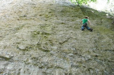 bir yaz orman Alpleri'nde dik bir teknik dikey rotasında erkek dağ Rehberi kaya tırmanma