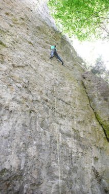 bir yaz orman Alpleri'nde dik bir teknik dikey rotasında erkek dağ Rehberi kaya tırmanma