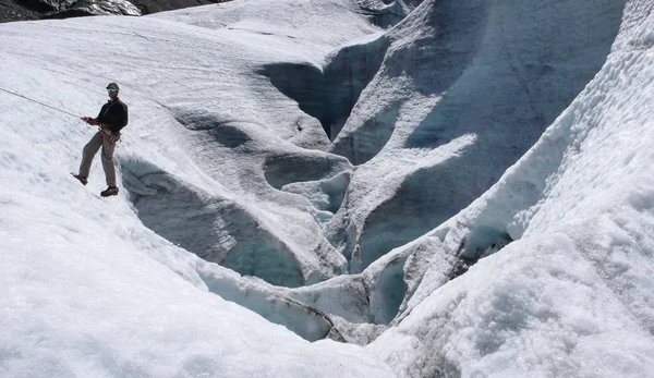 young male mountain guide training ice and rope skills for mountain climbing on a glacier on a beautiful summer day