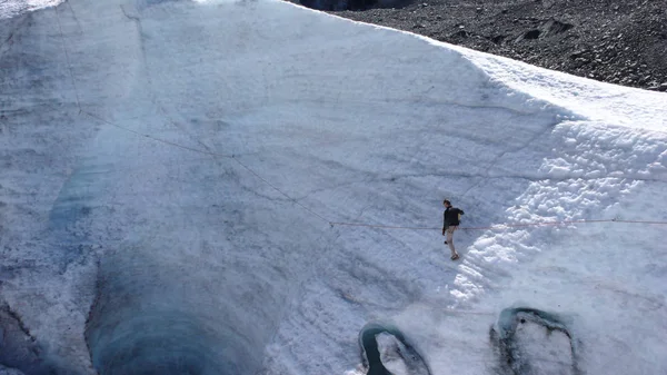 young male mountain guide training ice and rope skills for mountain climbing on a glacier on a beautiful summer day