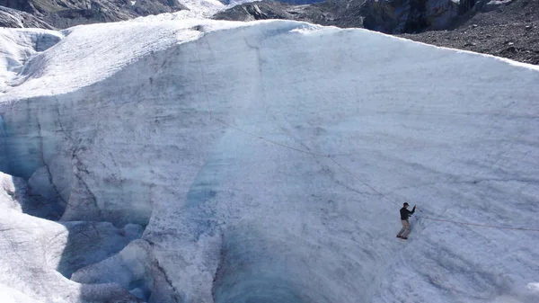 young male mountain guide training ice and rope skills for mountain climbing on a glacier on a beautiful summer day