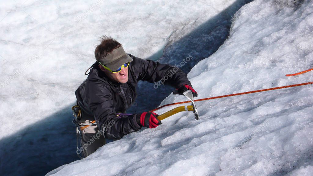 young male mountain guide training ice and rope skills for mountain climbing on a glacier on a beautiful summer day