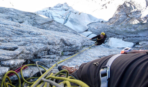 горный гид на твердом гранитном восхождении на высокую альпийскую вершину в швейцарских Альпах

