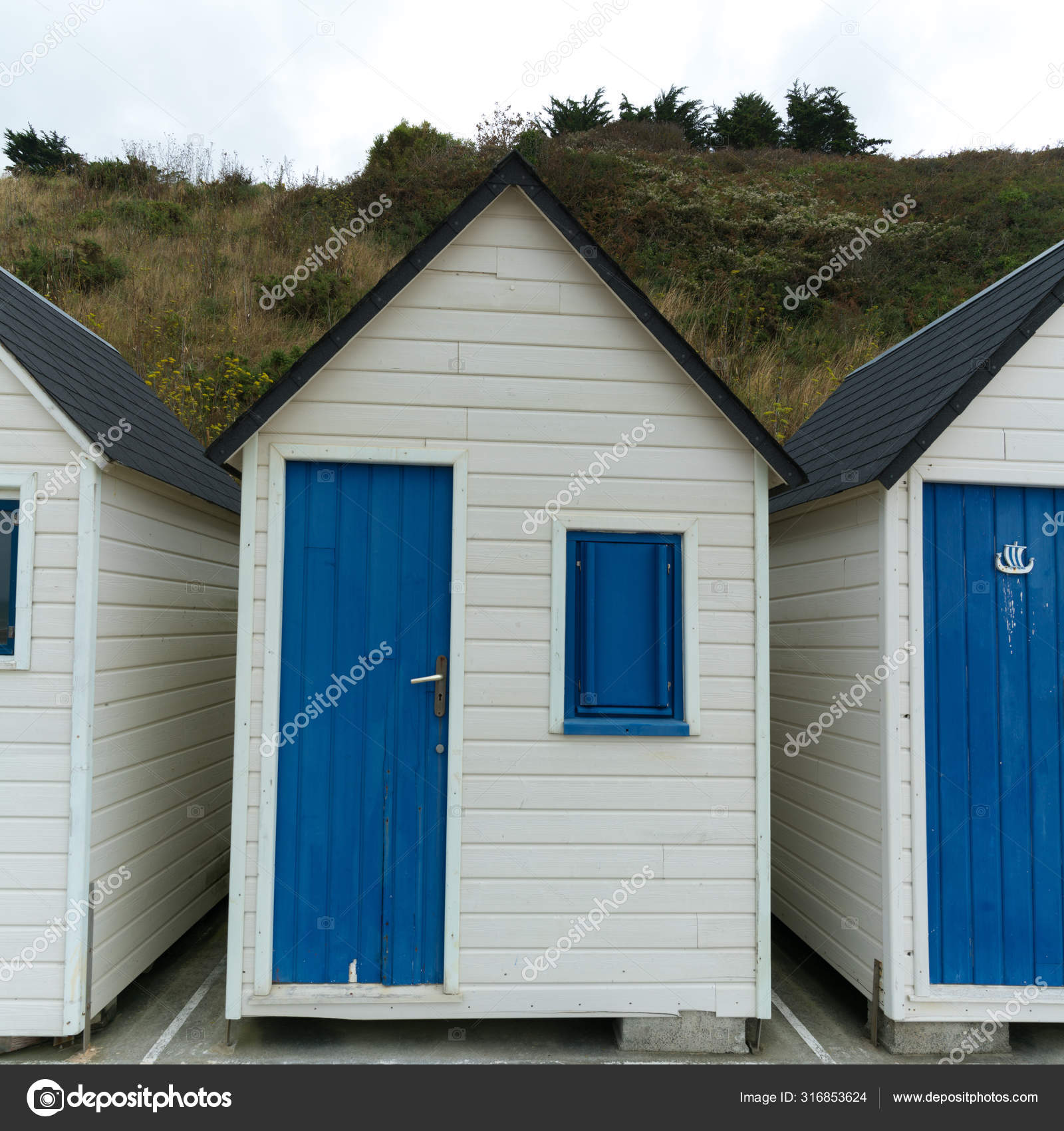 Row Of Small Wooden Beach Cottages On The Rocky Normandy Coast