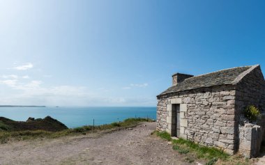 Brittany 'nin vahşi sahillerindeki taştan kulübe.