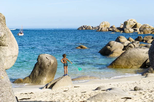 Jeune pêcheur debout sur un rocher à la plage avec un filet — Photo