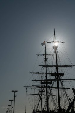 Direk silueti ve mavi gökyüzünün altındaki eski bir yelkenli donanımı.
