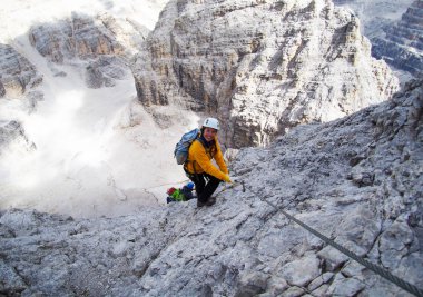 Çekici dağcı dik ve sert bir Via Ferrata tırmanışında