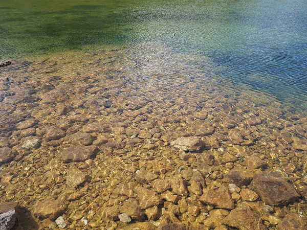 Abstracta vista de cerca del agua clara del lago de montaña y las rocas — Foto de Stock
