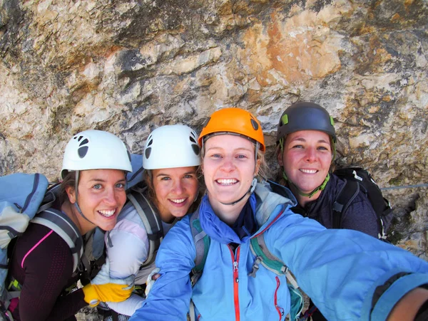 Four female climbers celebrate on the mountain summit by taking — Stock Photo, Image