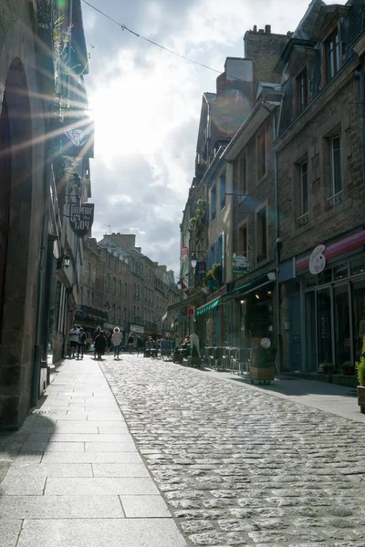 Turister njuta av ett besök i den historiska gamla staden Dinan i Bretagne med solen långsamt sjunkande — Stockfoto