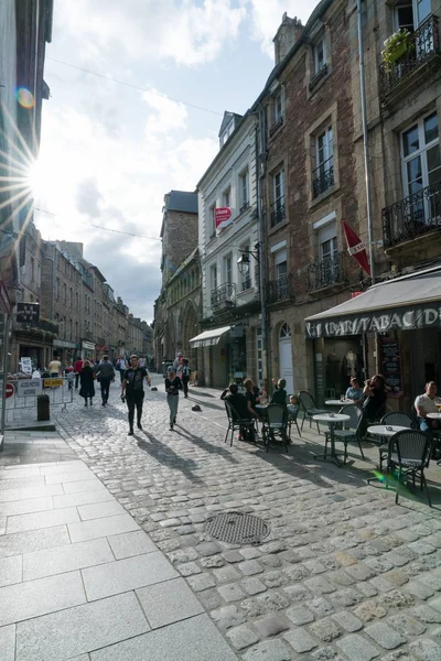 Turister njuta av ett besök i den historiska gamla staden Dinan i Bretagne med solen långsamt sjunkande — Stockfoto