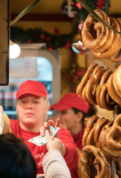 Vrouw die heerlijke verse pretzels verkoopt van een marktkraam — Stockfoto