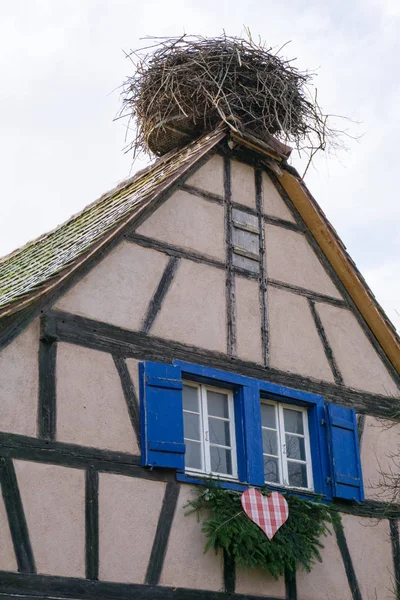 Large stork nest on the roof gable of a traditional wooden half- — Stock Photo, Image