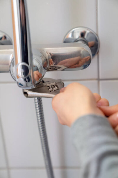 woman plumber changing a chrome shower house on a shower faucet during bath renovation work