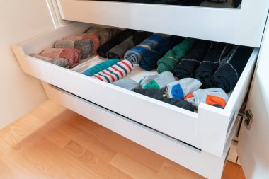 many colorful men's socks in a plain white wooden sock drawer clipart